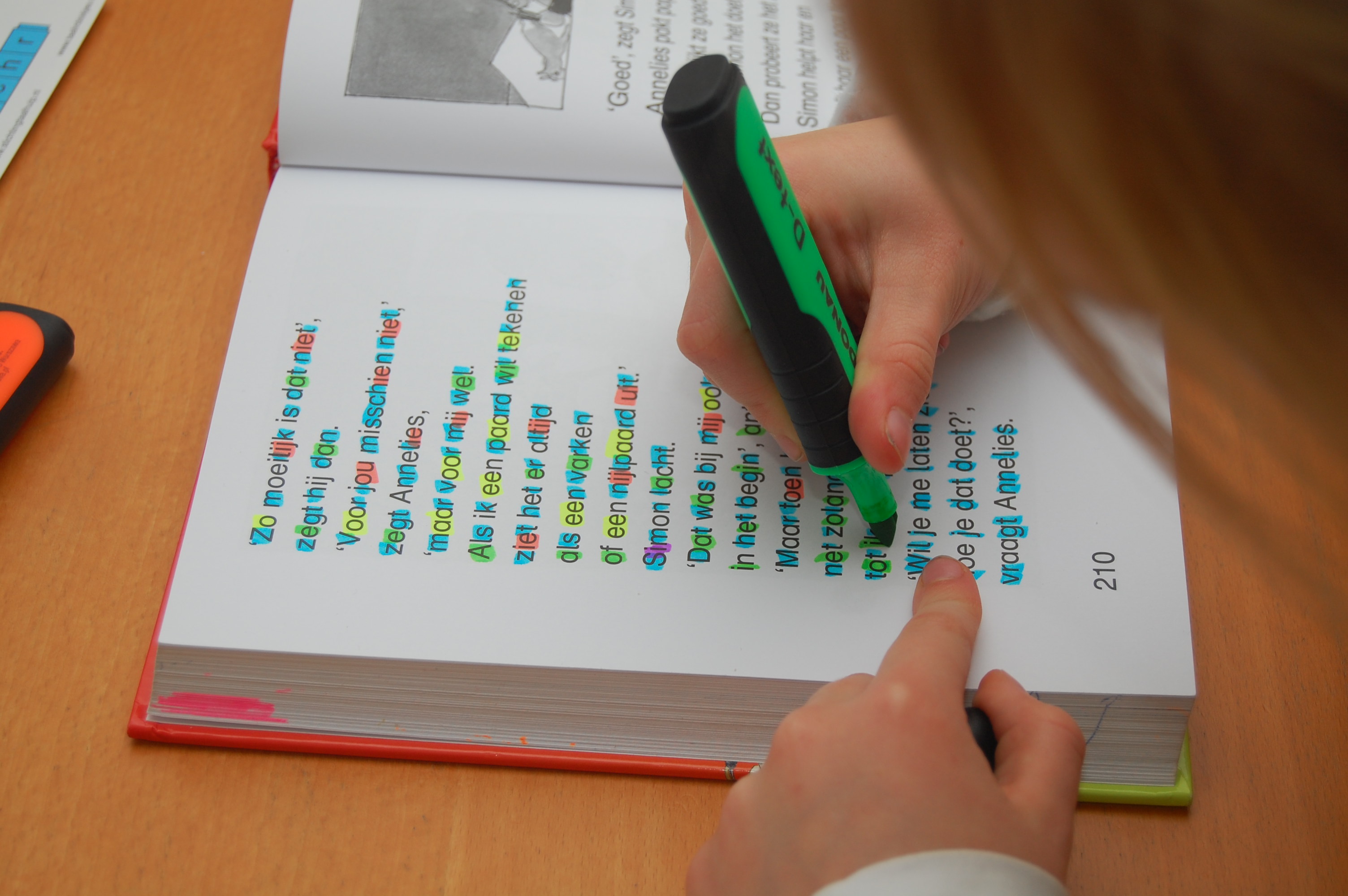Een meisje kleurt met een stift de letters in een boek
