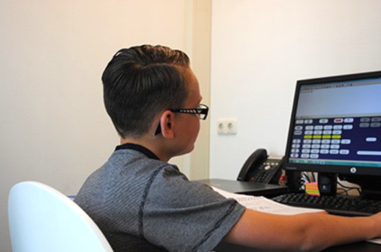 Foto uit de folder van Dekker & Dooyeweerd, een jongen die met een computerprogramma bezig is.